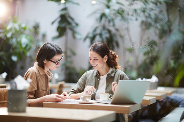 Jolly ladies viewing papers in cafe - Stock Photo - Images