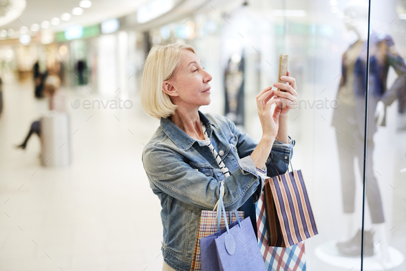 Content woman photographing favorite outfit in mall - Stock Photo - Images