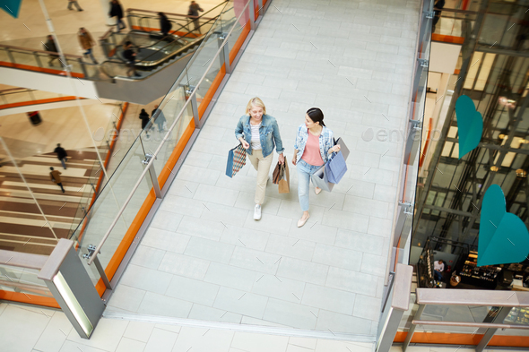 Excited mother and daughter talking while walking over mall - Stock Photo - Images