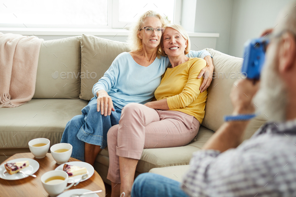 Happy ladies friends hugging on sofa - Stock Photo - Images
