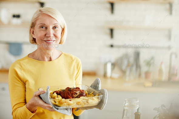 Careful mature lady with cooked meat - Stock Photo - Images