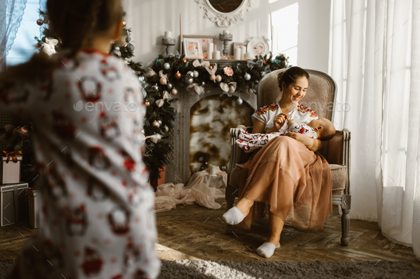 Beautiful mother sits in the armchair with her little baby next - Stock Photo - Images