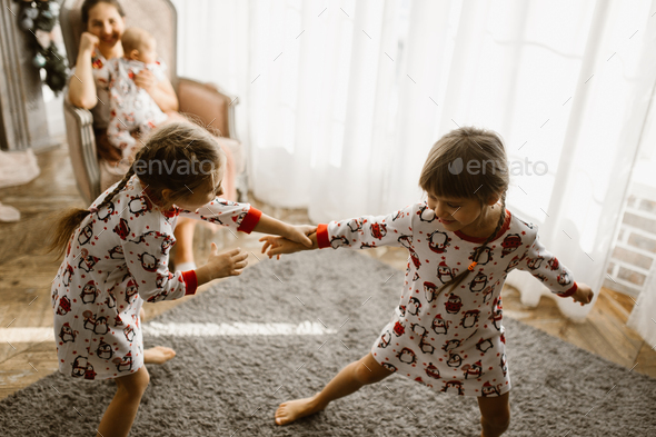 Beautiful mother sits in the armchair with her little baby next to the fireplace and New Year's - Stock Photo - Images