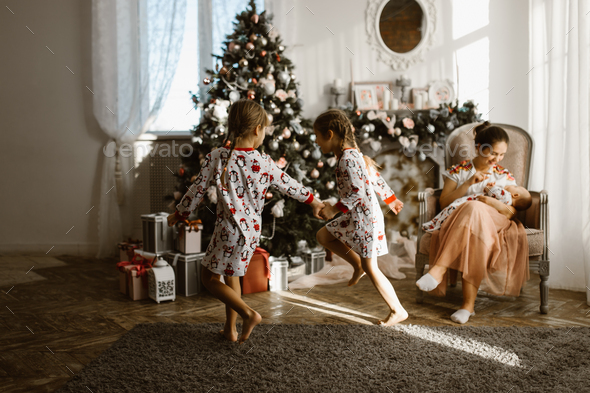 Two little sisters in pajamas having fun New Year's tree with gi - Stock Photo - Images
