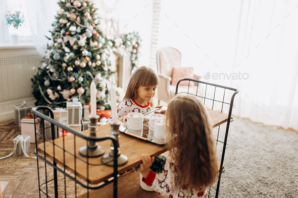 Two charming little girls sit at the table and are going to drink cocoa with Marshmallows and - Stock Photo - Images