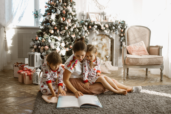 Young beautiful mother with two little daughters sit on the carp - Stock Photo - Images