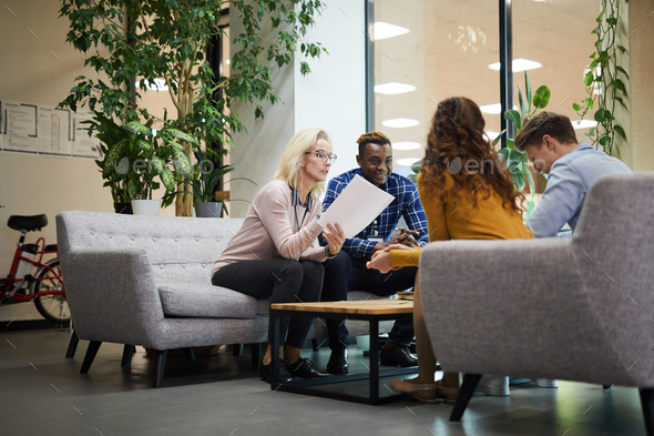 Lady reading report to colleagues at meeting - Stock Photo - Images