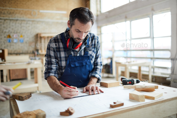 Thoughtful carpenter making sketch - Stock Photo - Images