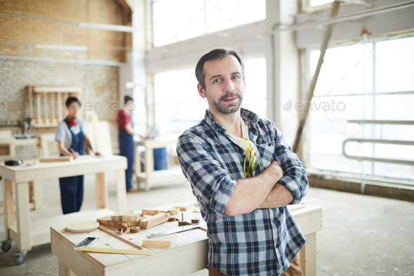 Confident workman in carpentry shop - Stock Photo - Images