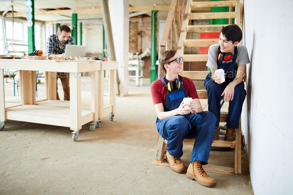 Positive workers drinking coffee in workshop - Stock Photo - Images