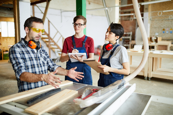 Skilled carpenter working with interns - Stock Photo - Images