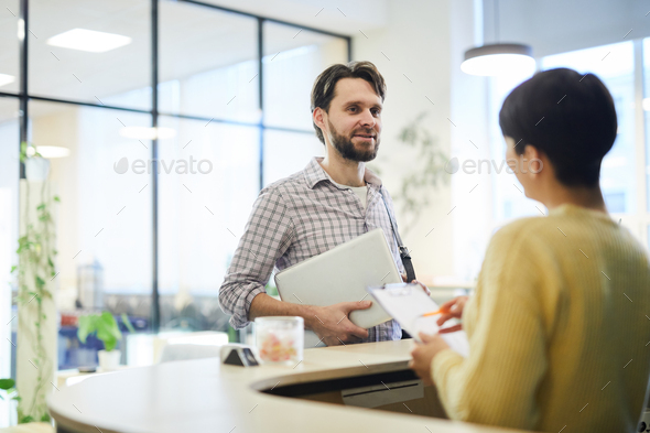 Young programmer talking to hotel receptionist - Stock Photo - Images