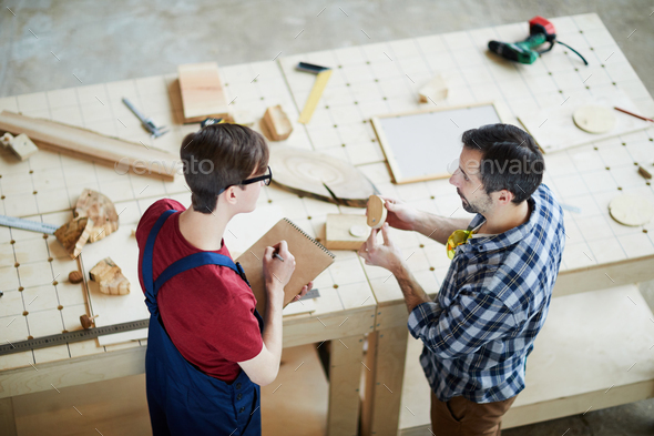 Middle-aged man showing wooden detail to colleague - Stock Photo - Images