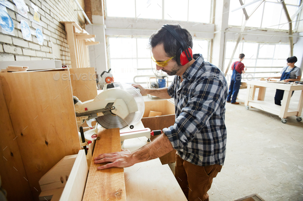 Concentrated man cutting wooden piece - Stock Photo - Images