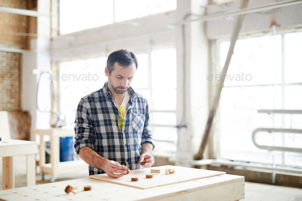 Busy workman comparing small wooden details - Stock Photo - Images