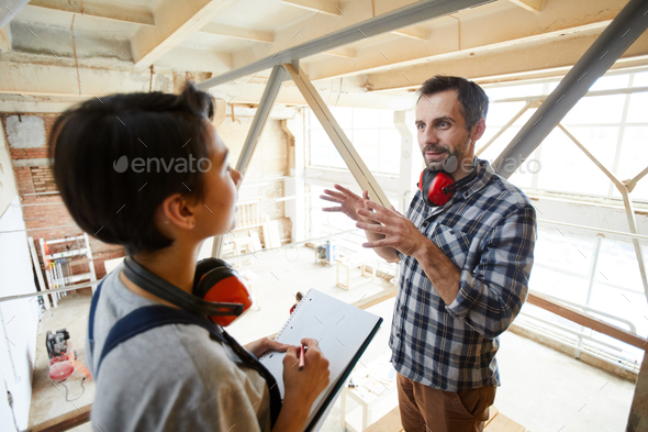 Carpenter explaining tasks to new employee - Stock Photo - Images