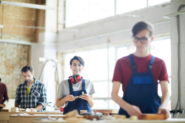 Cheerful lady working in carpentry shop - Stock Photo - Images