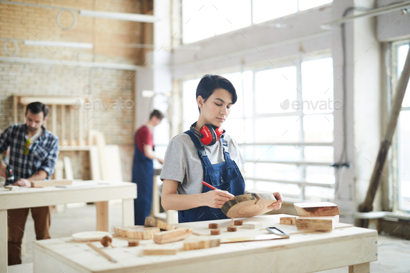 Masculine girl drawing on slice of wood - Stock Photo - Images