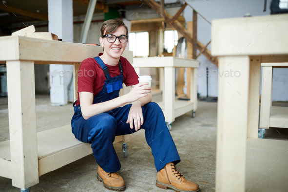 Positive young carpenter drinking coffee - Stock Photo - Images