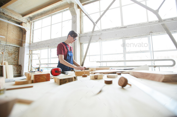 Busy guy in carpentry workshop full of light - Stock Photo - Images