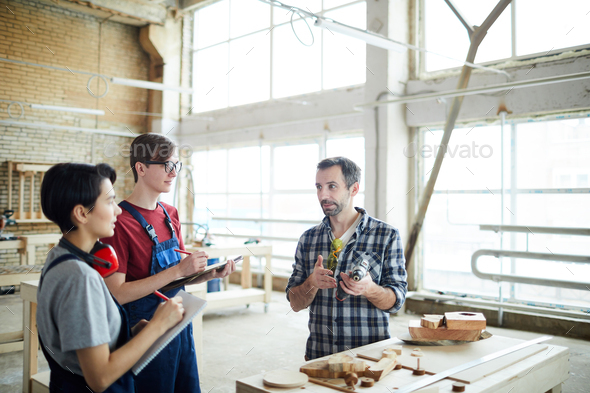 Teaching carpentry students in workshop - Stock Photo - Images
