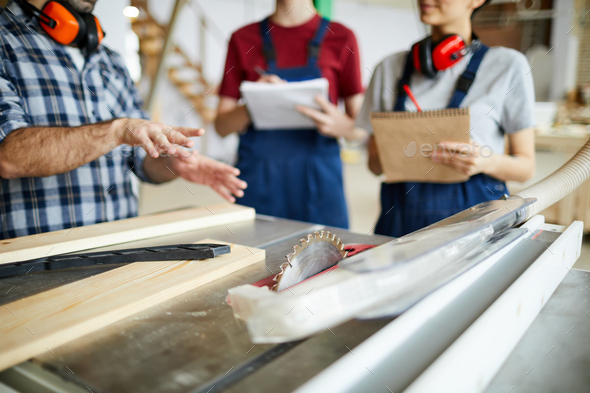 Carpenter showing circular saw table to students - Stock Photo - Images
