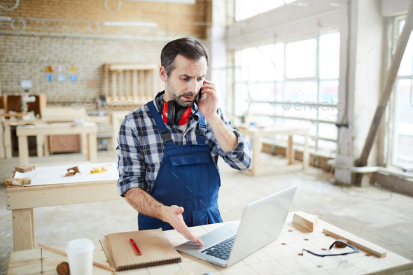 Frowning man talking to customer on phone - Stock Photo - Images