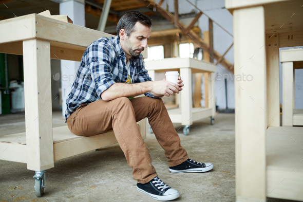 Sad carpenter drinking coffee - Stock Photo - Images