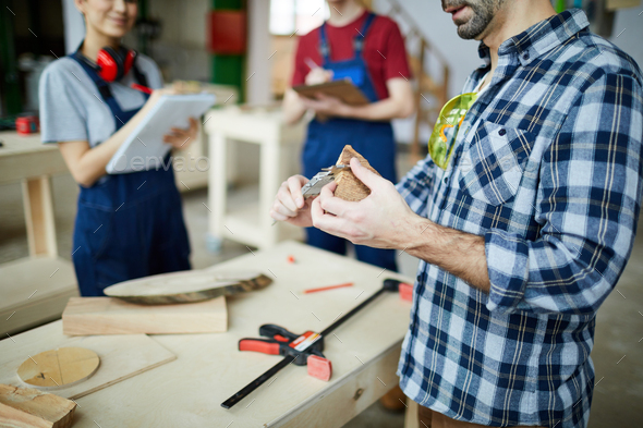 Measuring distance between opposite sides of wooden piece with caliper - Stock Photo - Images