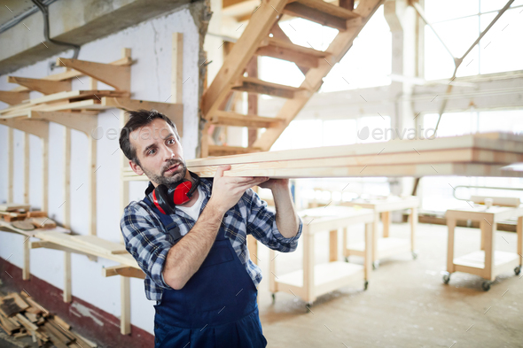 Builder carrying wooden planks - Stock Photo - Images