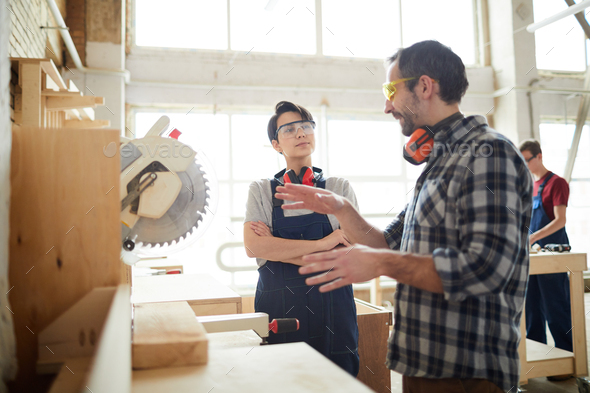 Carpenter giving advice to lady how to use circular saw - Stock Photo - Images