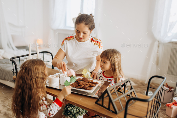 Young beautiful mother and her two charming little daughters sit - Stock Photo - Images