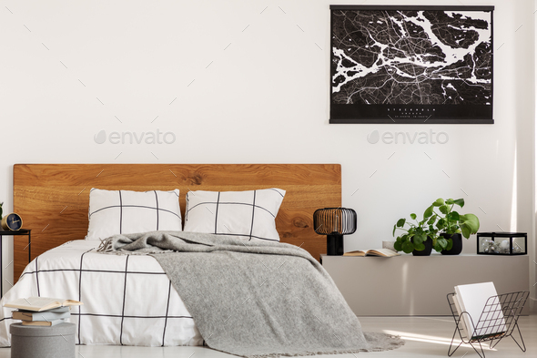 Copy space on white wall with black map in modern bedroom with king size bed with wooden headboard - Stock Photo - Images