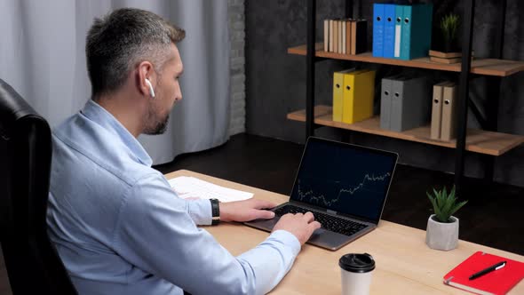 Smiling Man Professional Trader Broker Uses Laptop with Stock Exchange Chart alt