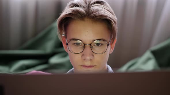 Teenage Boy in Glasses Looking at Laptop Screen alt