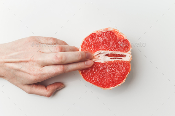 Sexual and female genital concept. Grapefruit and women's fingers like vagina and clitoris