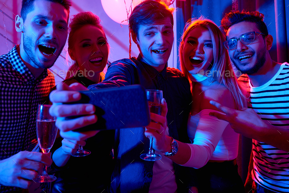 friends with smartphone taking selfie in club, Stock image