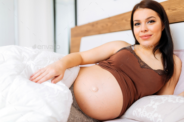 Portrait of pregnant woman in bed - Stock Photo - Images