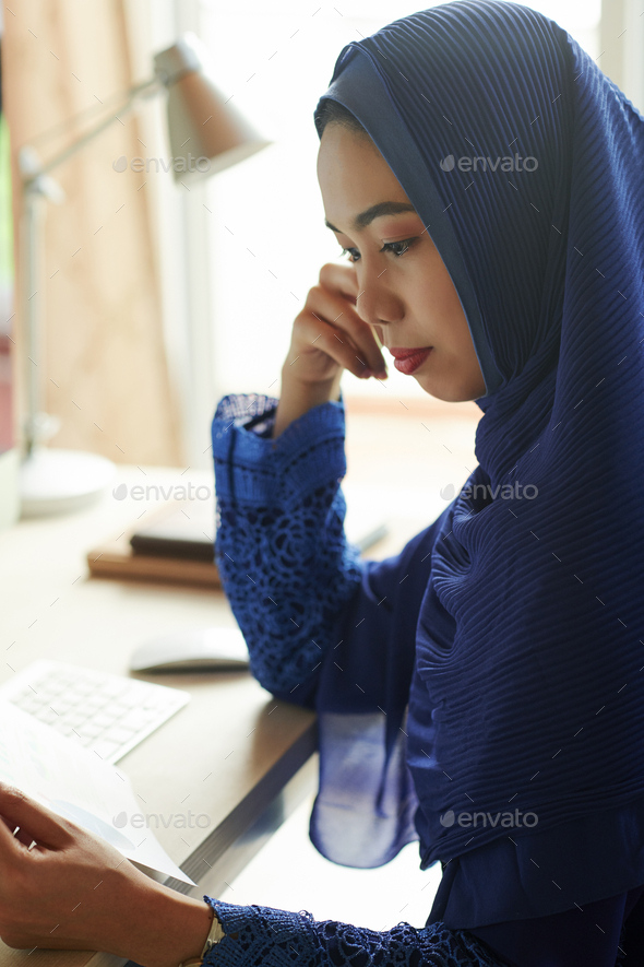 Muslim woman reading document - Stock Photo - Images