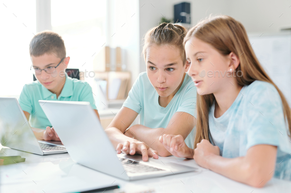Middle school boy and girl looking at curious stuff on laptop display - Stock Photo - Images