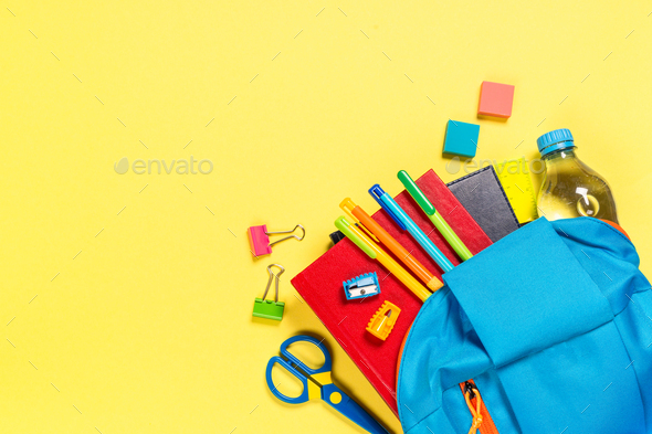 School backpack with stationery on yellow background