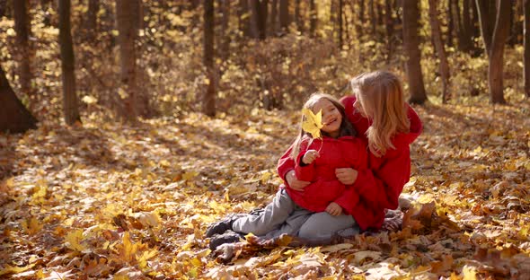Mother with Daughter Sitting on a Blanket in the Autumn Forest alt