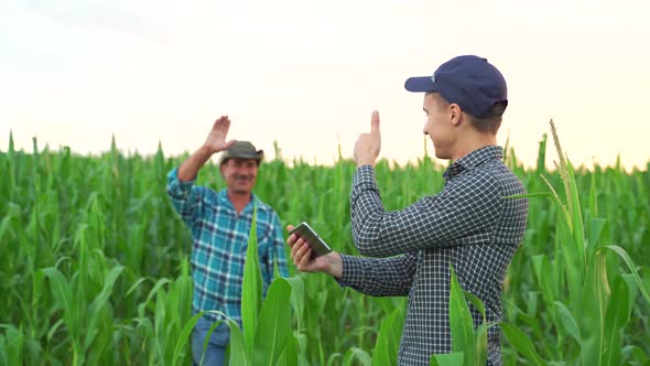 Son and Father Farmers Standing in a Corn Field with Tablet alt