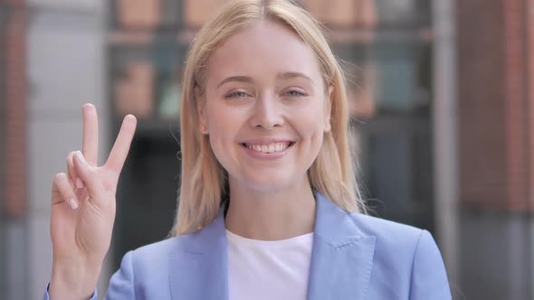 Sign of Victory By Young Businesswoman Standing Outdoor alt