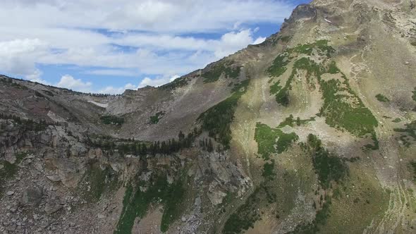 Camera pan follows cloud cover along a mountainside to reveal lakes in the distance alt
