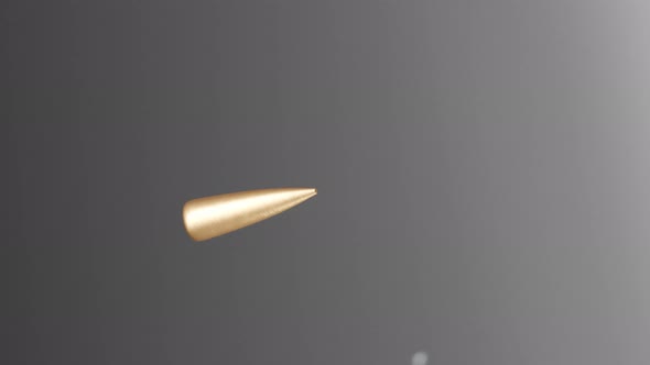 Slow-motion shot of a shiny bullet shattering a piece of transparent glass. 4KHD alt