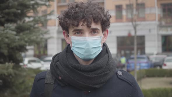 Close-up Portrait of Young Caucasian Boy in Face Mask Posing on City Street. Handsome Brunette Guy alt