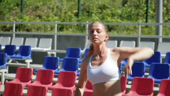 Young Fit Busty Woman with Ponytail in Sportswear Stretching at Sports Ground