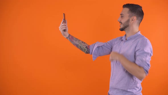 Man with Tattoo Sleeve on Arm Using Smartphone To Video Call a Friend, Studio Shot alt