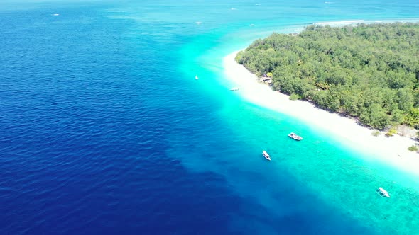 Vivid colors of deep blue ocean and bright turquoise lagoon around tropical island with white beach alt